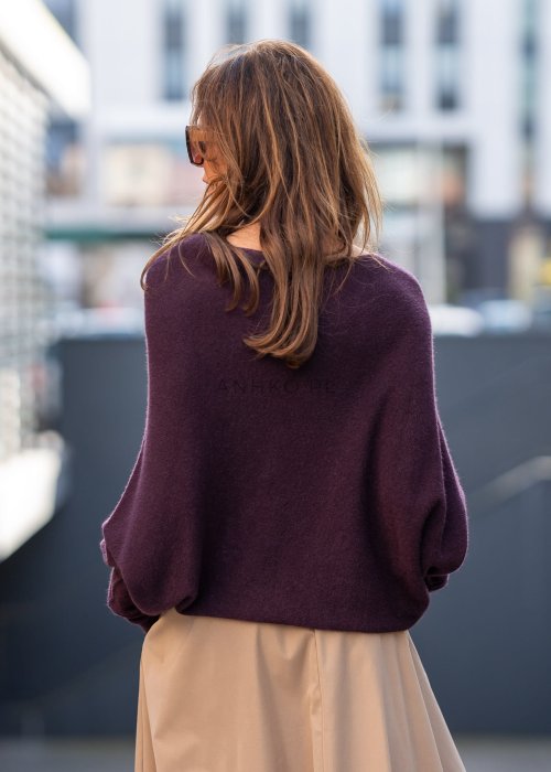 Śliwkowy sweter damski oversize o nietoperzowym kroju z dekoltem łódka, luźna elegancka stylizacja miejska.