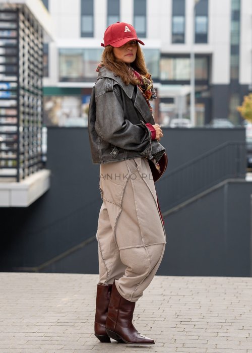 Beżowe spodnie oversize z obniżonym krokiem i dekoracyjnymi przeszyciami, luźny fason, miejska stylizacja damska.