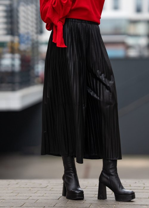 Czarne spodnie damskie z połyskującej tkaniny, plisowane, o długości 7/8, w stylu eleganckim i nowoczesnym