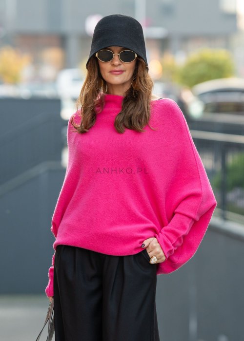 Fuksjowy sweter damski oversize o nietoperzowym kroju z dekoltem łódka, wyrazista stylizacja miejska.