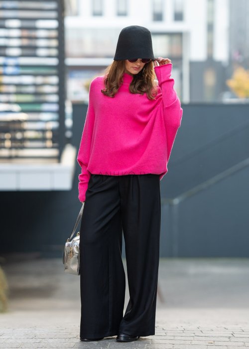 Fuksjowy sweter damski oversize o nietoperzowym kroju z dekoltem łódka, wyrazista stylizacja miejska.