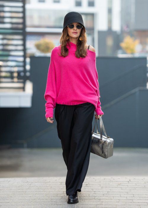 Fuksjowy sweter damski oversize o nietoperzowym kroju z dekoltem łódka, wyrazista stylizacja miejska.