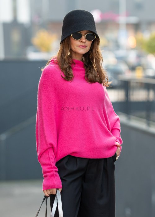 Fuksjowy sweter damski oversize o nietoperzowym kroju z dekoltem łódka, wyrazista stylizacja miejska.