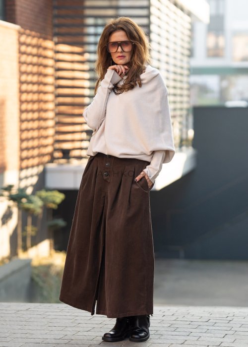 Śmietankowy sweter damski oversize o nietoperzowym kroju z asymetrycznym dołem, stylizacja miejska z szerokimi spodniami.