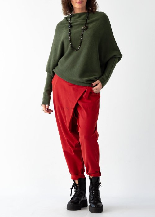 Khaki sweter oversize o nietoperzowym kroju z dekoltem łódka i asymetrycznym dołem zestawiony z czerwonymi szerokimi spodniami i długim naszyjnikiem.