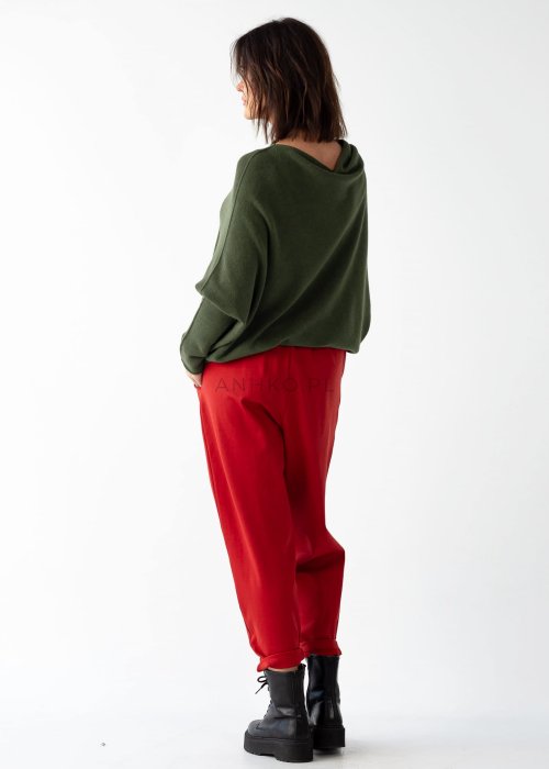 Khaki sweter oversize o nietoperzowym kroju z dekoltem łódka i asymetrycznym dołem zestawiony z czerwonymi szerokimi spodniami i długim naszyjnikiem.