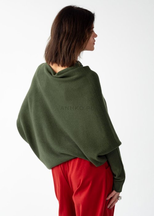 Khaki sweter oversize o nietoperzowym kroju z dekoltem łódka i asymetrycznym dołem zestawiony z czerwonymi szerokimi spodniami i długim naszyjnikiem.