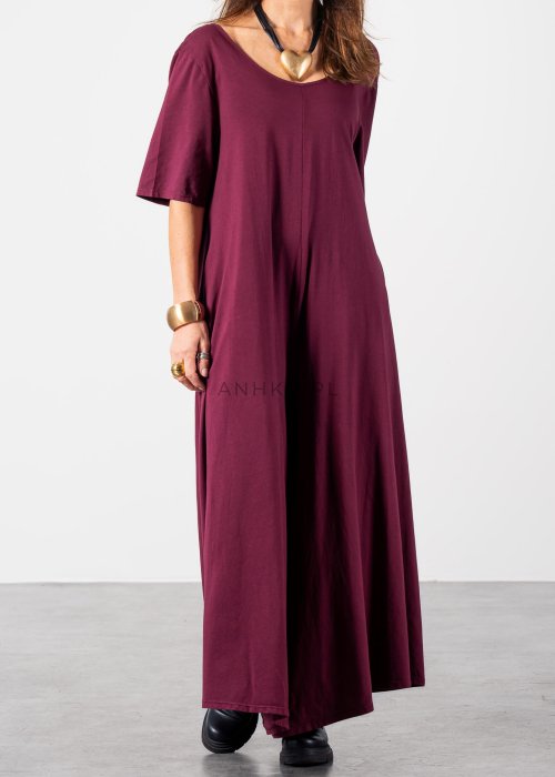 Śliwkowy kombinezon damski oversize z szeroką nogawką i krótkim rękawem, z głębokim wycięciem na plecach w stylizacji z biżuterią i okularami przeciwsłonecznymi.