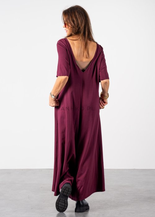 Śliwkowy kombinezon damski oversize z szeroką nogawką i krótkim rękawem, z głębokim wycięciem na plecach w stylizacji z biżuterią i okularami przeciwsłonecznymi.