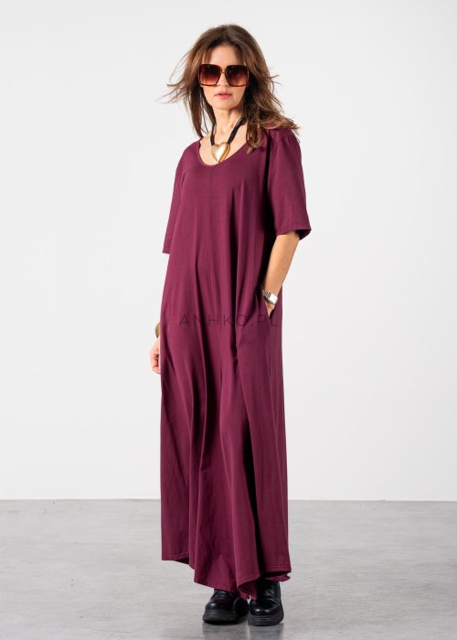 Śliwkowy kombinezon damski oversize z szeroką nogawką i krótkim rękawem, z głębokim wycięciem na plecach w stylizacji z biżuterią i okularami przeciwsłonecznymi.