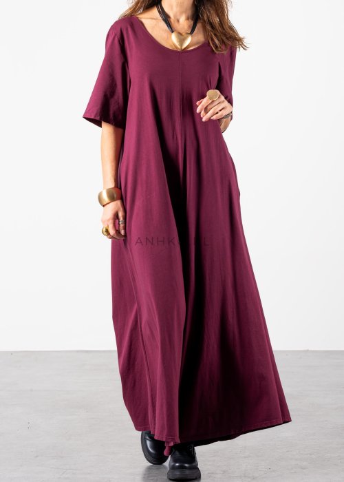 Śliwkowy kombinezon damski oversize z szeroką nogawką i krótkim rękawem, z głębokim wycięciem na plecach w stylizacji z biżuterią i okularami przeciwsłonecznymi.