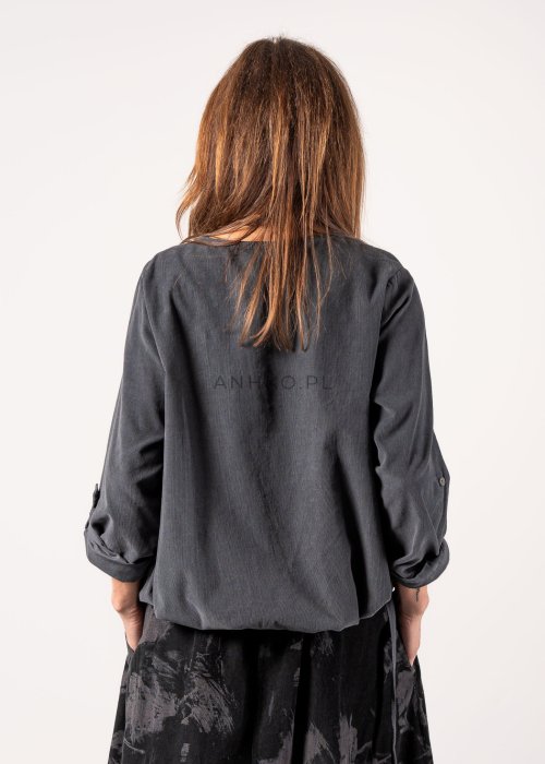 Szara bluzka damska oversize z długim rękawem i regulowanym dołem, minimalistyczny fason w stylizacji z czarną spódnicą midi i botkami.