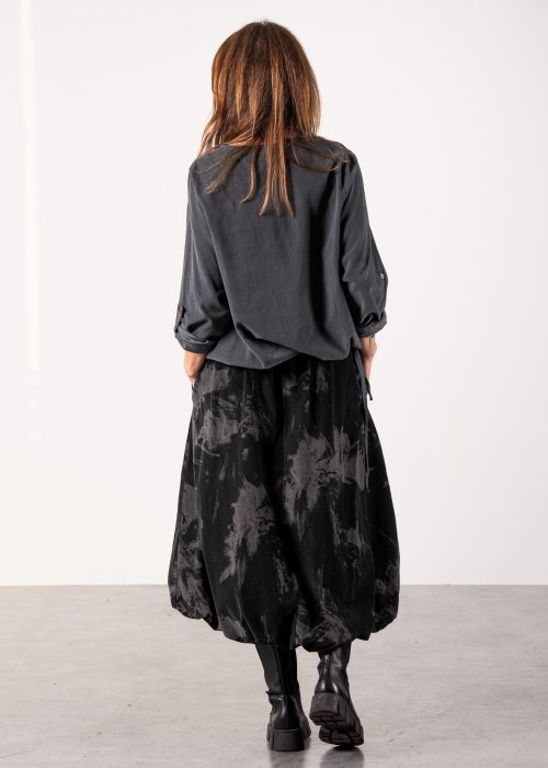 Szara bluzka damska oversize z długim rękawem i regulowanym dołem, minimalistyczny fason w stylizacji z czarną spódnicą midi i botkami.