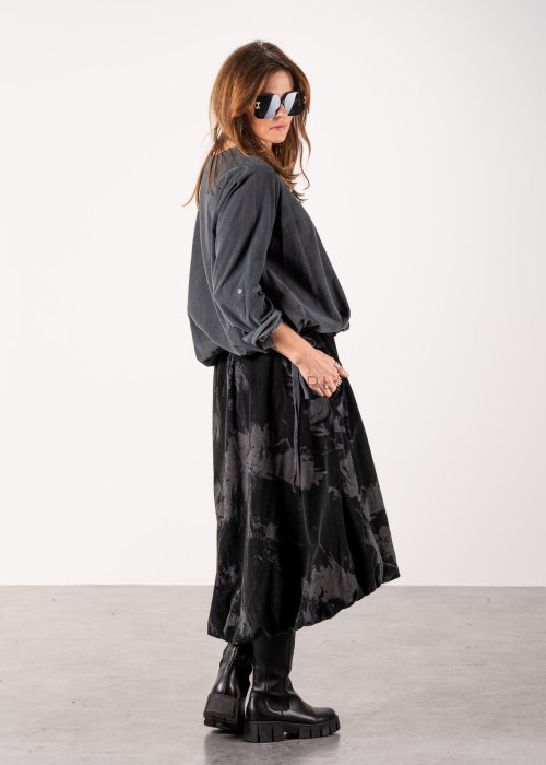 Szara bluzka damska oversize z długim rękawem i regulowanym dołem, minimalistyczny fason w stylizacji z czarną spódnicą midi i botkami.