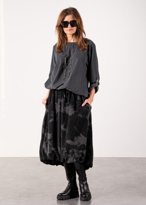 Szara bluzka damska oversize z długim rękawem i regulowanym dołem, minimalistyczny fason w stylizacji z czarną spódnicą midi i botkami.