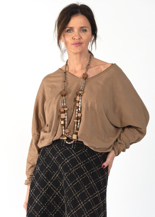 Brązowa bluzka damska oversize z długim rękawem i dekoltem V. Model prezentowany w stylizacji z czarną spódnicą w kratę i długim naszyjnikiem.