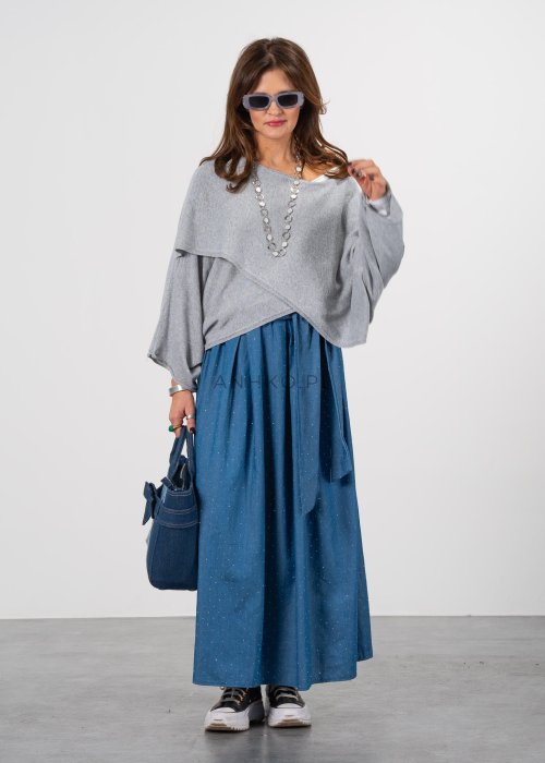 Szary sweter damski oversize z asymetrycznym dołem i szerokimi rękawami, stylizacja z niebieską spódnicą i torebką.