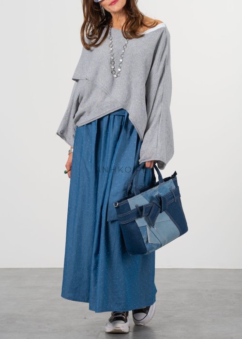 Szary sweter damski oversize z asymetrycznym dołem i szerokimi rękawami, stylizacja z niebieską spódnicą i torebką.