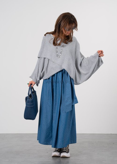 Szary sweter damski oversize z asymetrycznym dołem i szerokimi rękawami, stylizacja z niebieską spódnicą i torebką.