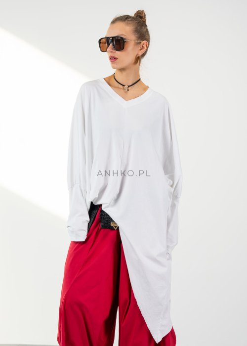Biała bluzka oversize damska z asymetrycznym dołem i dekoltem V. Stylizacja z czerwonymi spodniami w nowoczesnym, minimalistycznym stylu.