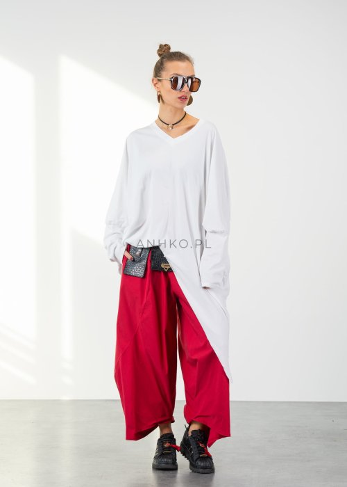 Biała bluzka oversize damska z asymetrycznym dołem i dekoltem V. Stylizacja z czerwonymi spodniami w nowoczesnym, minimalistycznym stylu.