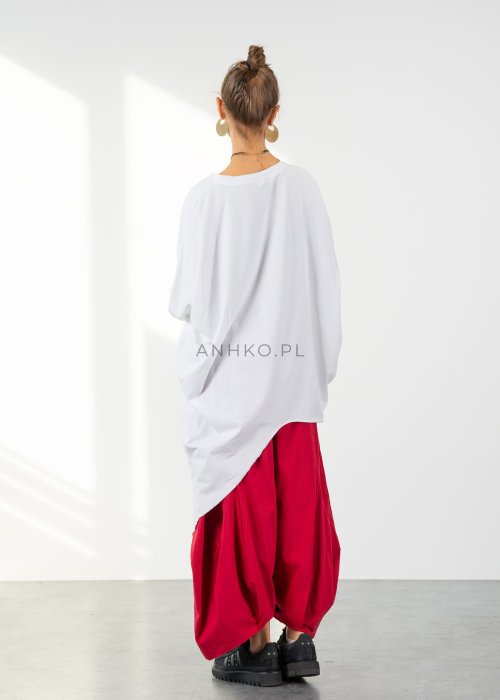 Biała bluzka oversize damska z asymetrycznym dołem i dekoltem V. Stylizacja z czerwonymi spodniami w nowoczesnym, minimalistycznym stylu.