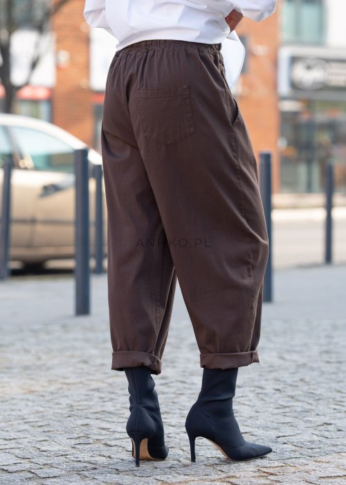 Brązowe spodnie damskie RelaxFit z elastycznym pasem i podwiniętymi nogawkami, stylizowane z białą koszulą oversize i botkami na obcasie w miejskim looku.