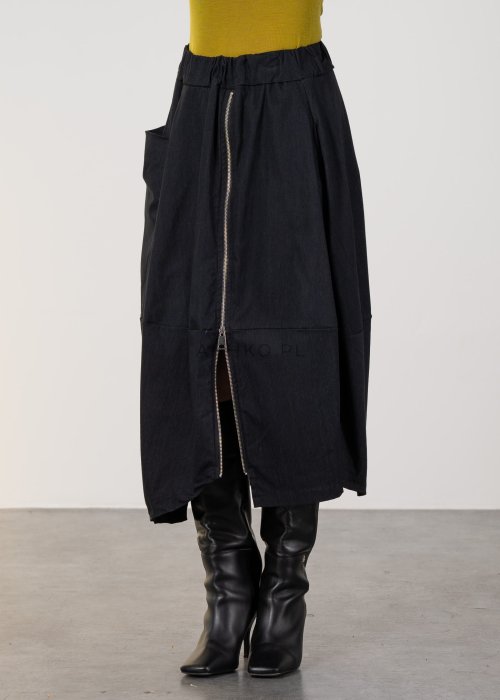 Grafitowa spódnica midi z asymetrycznym dołem i długim zamkiem z przodu, z elastyczną talią i kieszeniami. Model pokazany w stylizacji z dopasowaną bluzką i czarnymi kozakami na obcasie.