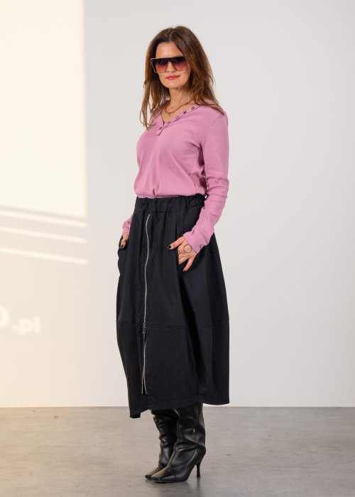 Grafitowa spódnica midi z asymetrycznym dołem i długim zamkiem z przodu, z elastyczną talią i kieszeniami. Model pokazany w stylizacji z dopasowaną bluzką i czarnymi kozakami na obcasie.