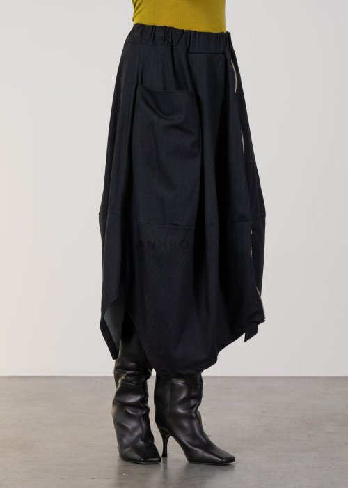 Grafitowa spódnica midi z asymetrycznym dołem i długim zamkiem z przodu, z elastyczną talią i kieszeniami. Model pokazany w stylizacji z dopasowaną bluzką i czarnymi kozakami na obcasie.