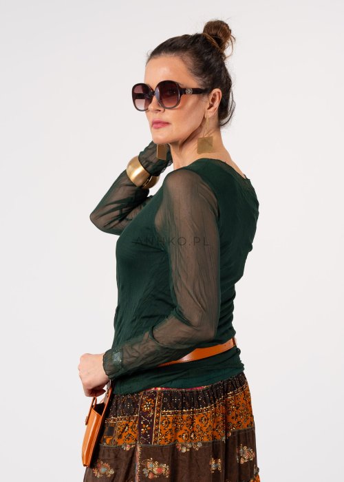 Ciemnozielona bluzka damska z transparentnymi rękawami i dekoltem łódka, elegancka stylizacja z paskiem i wzorzystą spódnicą.