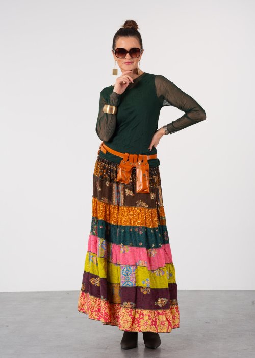 Ciemnozielona bluzka damska z transparentnymi rękawami i dekoltem łódka, elegancka stylizacja z paskiem i wzorzystą spódnicą.