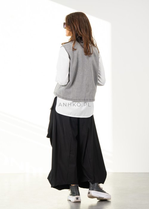 Damskie czarne spodnie parachute o szerokim kroju z dużymi kieszeniami i gumką w pasie, zestawione ze sneakersami. Model o luźnej, objętościowej formie.