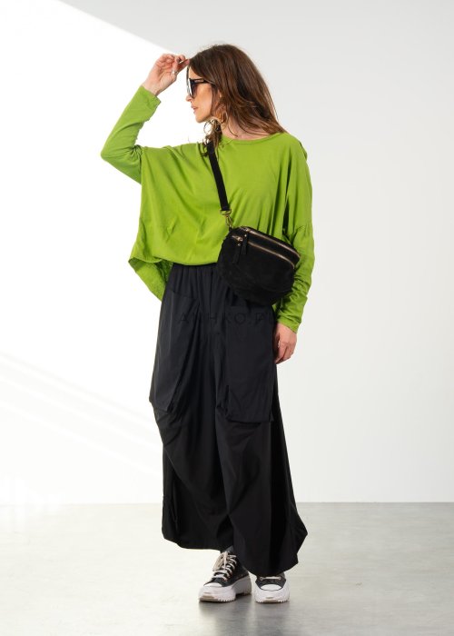 Damskie czarne spodnie parachute o szerokim kroju z dużymi kieszeniami i gumką w pasie, zestawione ze sneakersami. Model o luźnej, objętościowej formie.