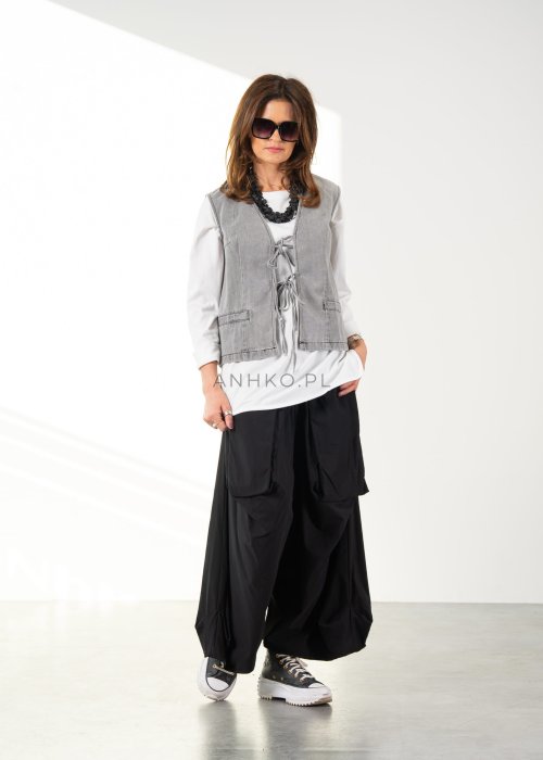 Damskie czarne spodnie parachute o szerokim kroju z dużymi kieszeniami i gumką w pasie, zestawione ze sneakersami. Model o luźnej, objętościowej formie.