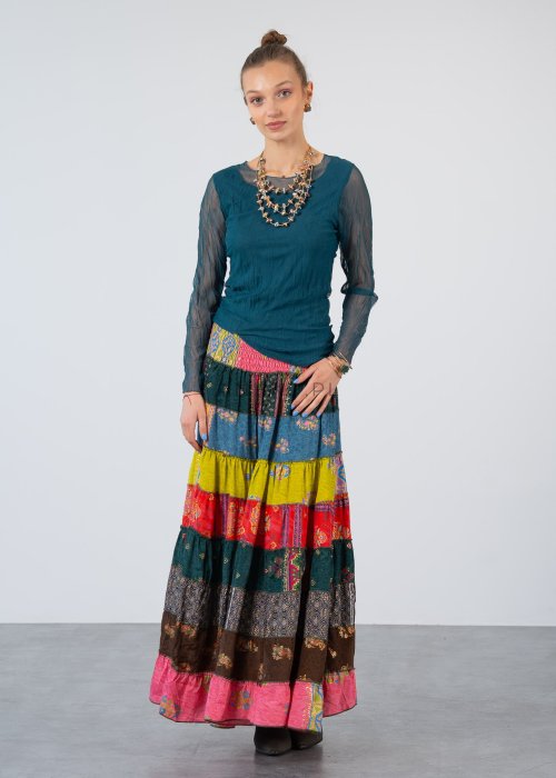 Morska bluzka damska z transparentnymi rękawami i dekoltem łódka, elegancka stylizacja z biżuterią i wzorzystą spódnicą.