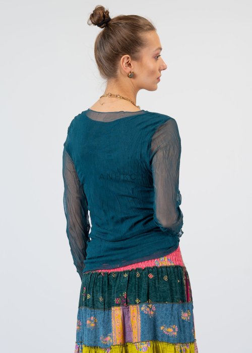 Morska bluzka damska z transparentnymi rękawami i dekoltem łódka, elegancka stylizacja z biżuterią i wzorzystą spódnicą.