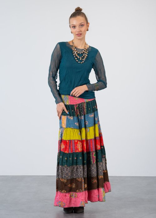 Morska bluzka damska z transparentnymi rękawami i dekoltem łódka, elegancka stylizacja z biżuterią i wzorzystą spódnicą.