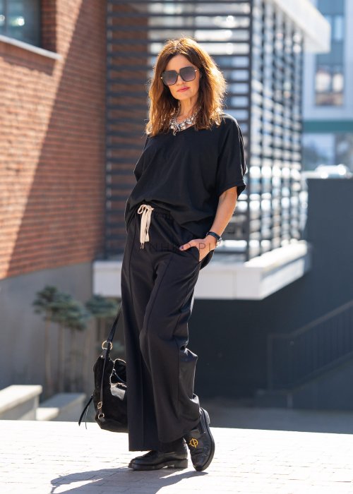 Czarne spodnie dresowe damskie z szeroką nogawką i elastyczną talią z troczkiem, stylizacja miejska