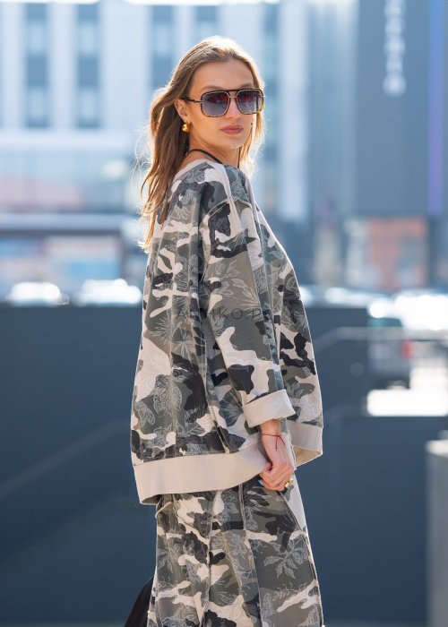 Damska bluza oversize w print moro z motywem roślinnym, z długim rękawem i okrągłym dekoltem. Stylizacja miejska zestawiona ze spodniami w tym samym wzorze i botkami.