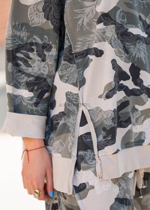 Damska bluza oversize w print moro z motywem roślinnym, z długim rękawem i okrągłym dekoltem. Stylizacja miejska zestawiona ze spodniami w tym samym wzorze i botkami.