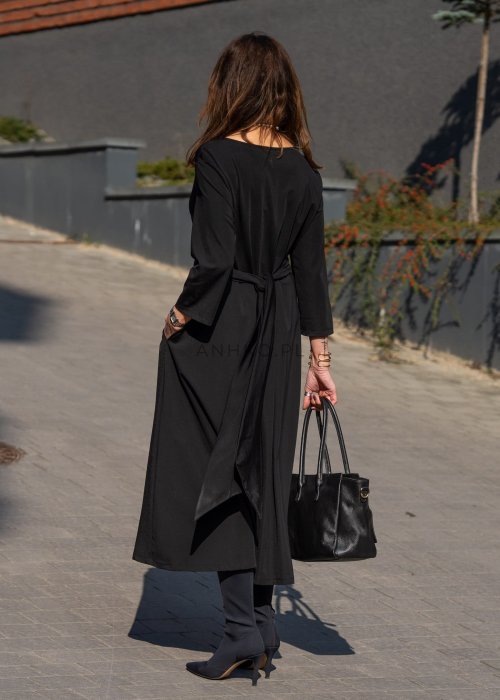 Czarna sukienka midi z wiązaniem w talii i rękawem 3/4, o lekko rozkloszowanym kroju. Stylizacja z botkami i torebką w eleganckim, miejskim wydaniu.
