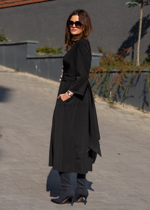 Czarna sukienka midi z wiązaniem w talii i rękawem 3/4, o lekko rozkloszowanym kroju. Stylizacja z botkami i torebką w eleganckim, miejskim wydaniu.