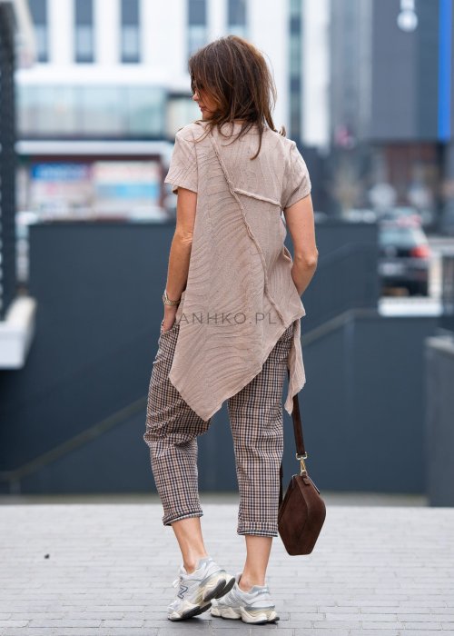 Beżowo-brązowe spodnie damskie w drobną kratę o długości 7/8 z elastyczną talią i kieszeniami, zestawione ze sneakersami w miejskiej stylizacji.