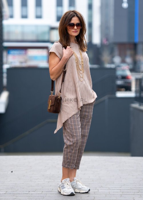 Beżowo-brązowe spodnie damskie w drobną kratę o długości 7/8 z elastyczną talią i kieszeniami, zestawione ze sneakersami w miejskiej stylizacji.