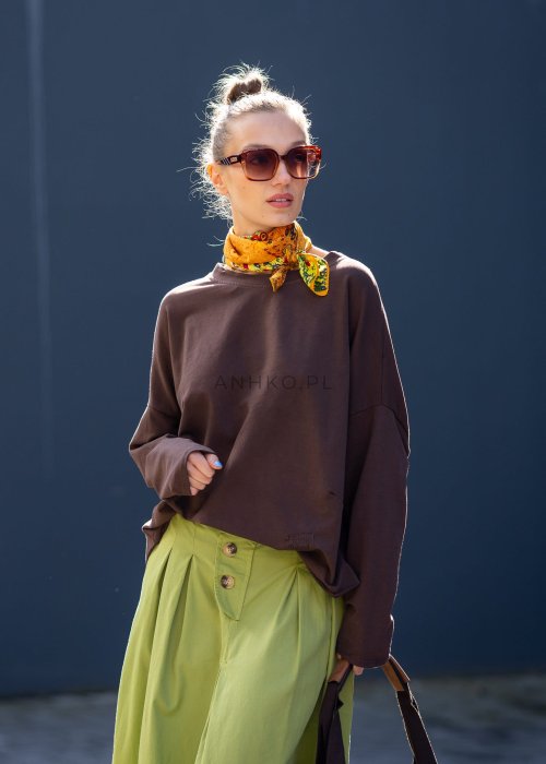 Czekoladowa bluza damska oversize z długim rękawem i subtelną naszywką na froncie. Luźny fason w stylizacji z szerokimi spodniami i apaszką w miejskim stylu.