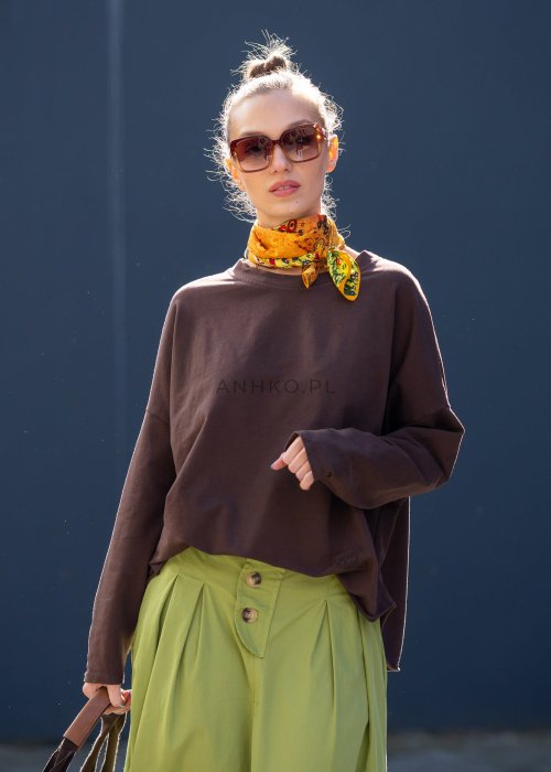 Czekoladowa bluza damska oversize z długim rękawem i subtelną naszywką na froncie. Luźny fason w stylizacji z szerokimi spodniami i apaszką w miejskim stylu.