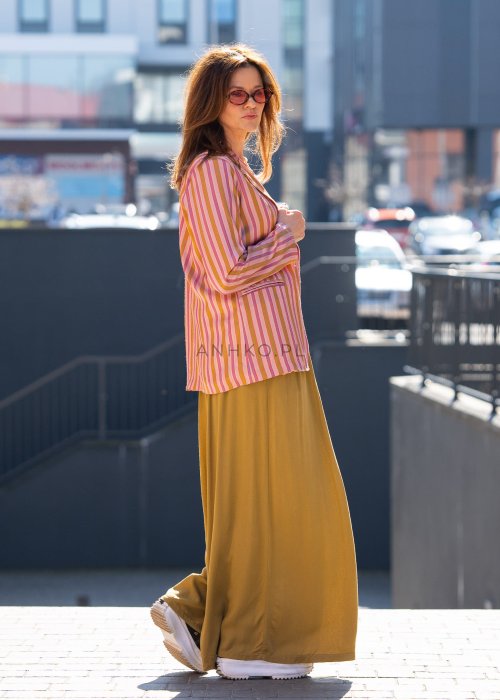Musztardowe spodnie damskie z szeroką, lejącą nogawką i elastycznym pasem, stylizowane z białym t-shirtem w casualowym, miejskim stylu.