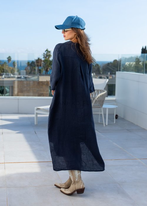 Granatowa lniana sukienka maxi w stylu szmizjerki, zapinana na guziki, o luźnym fasonie oversize, stylizowana z kowbojkami i czapką.