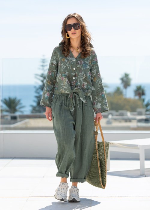 Lniana koszula damska w kolorze khaki z botanicznym printem w pastelowych barwach, o luźnym asymetrycznym kroju, zestawiona z lnianymi spodniami w tym samym odcieniu.